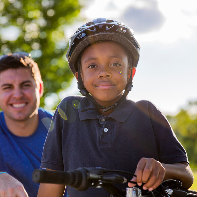 Portrait of male Little on bike with Big in the background