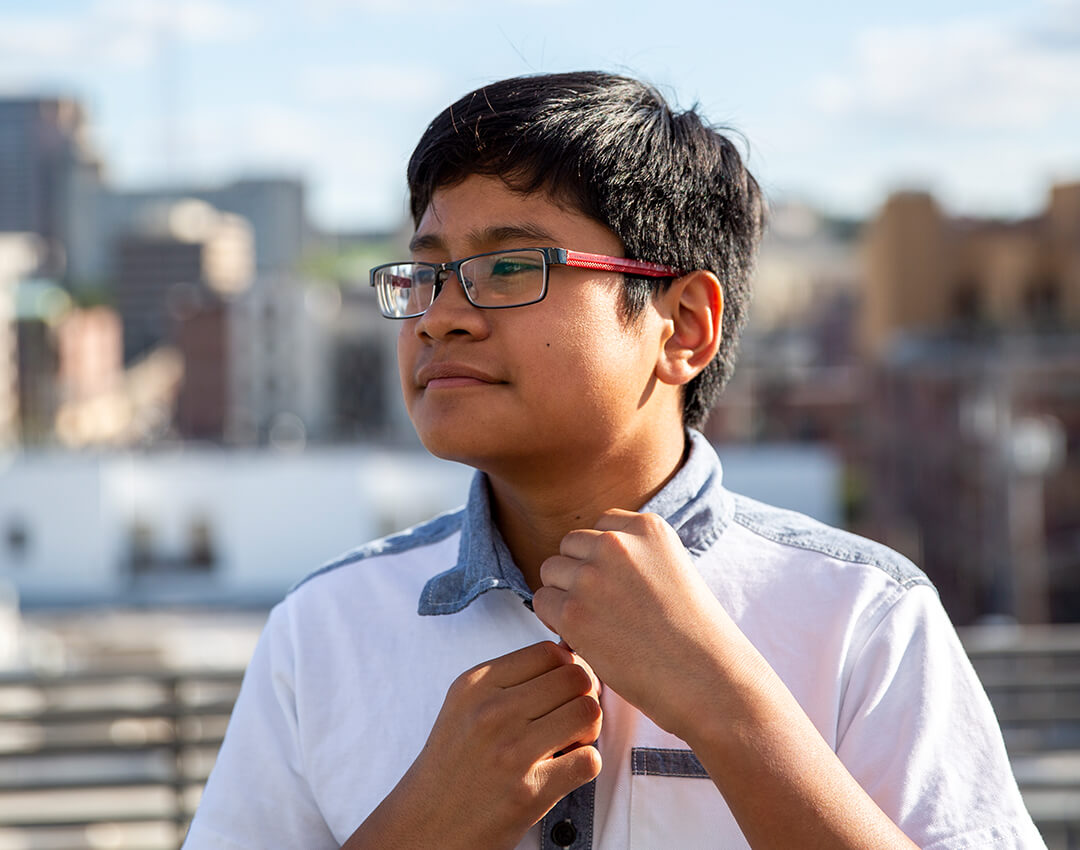 Hispanic Little looking into the distance with city building in background