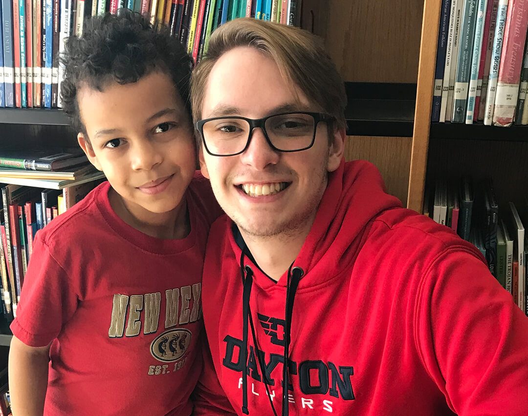 Big and Little posing for a picture with books in the background.